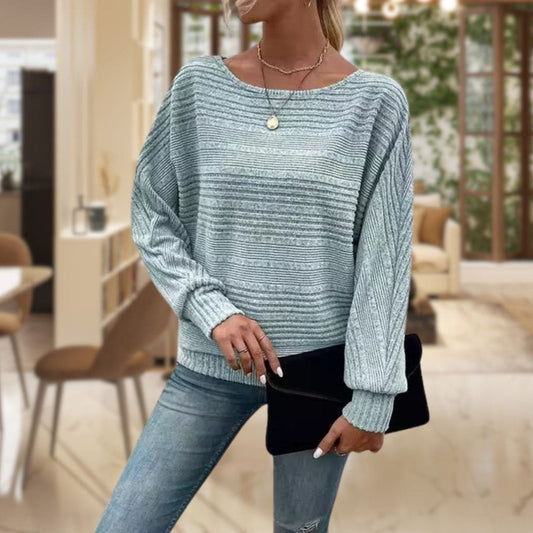 Model iført en lys struktureret sweater med rillestrik og afslappet pasform, stylet med jeans og lagdelte halskæder_0