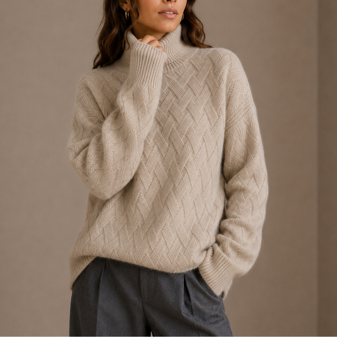 Kvinde iført en beige sweater med høj hals og struktureret flettemønster kombineret med mørke bukser._0