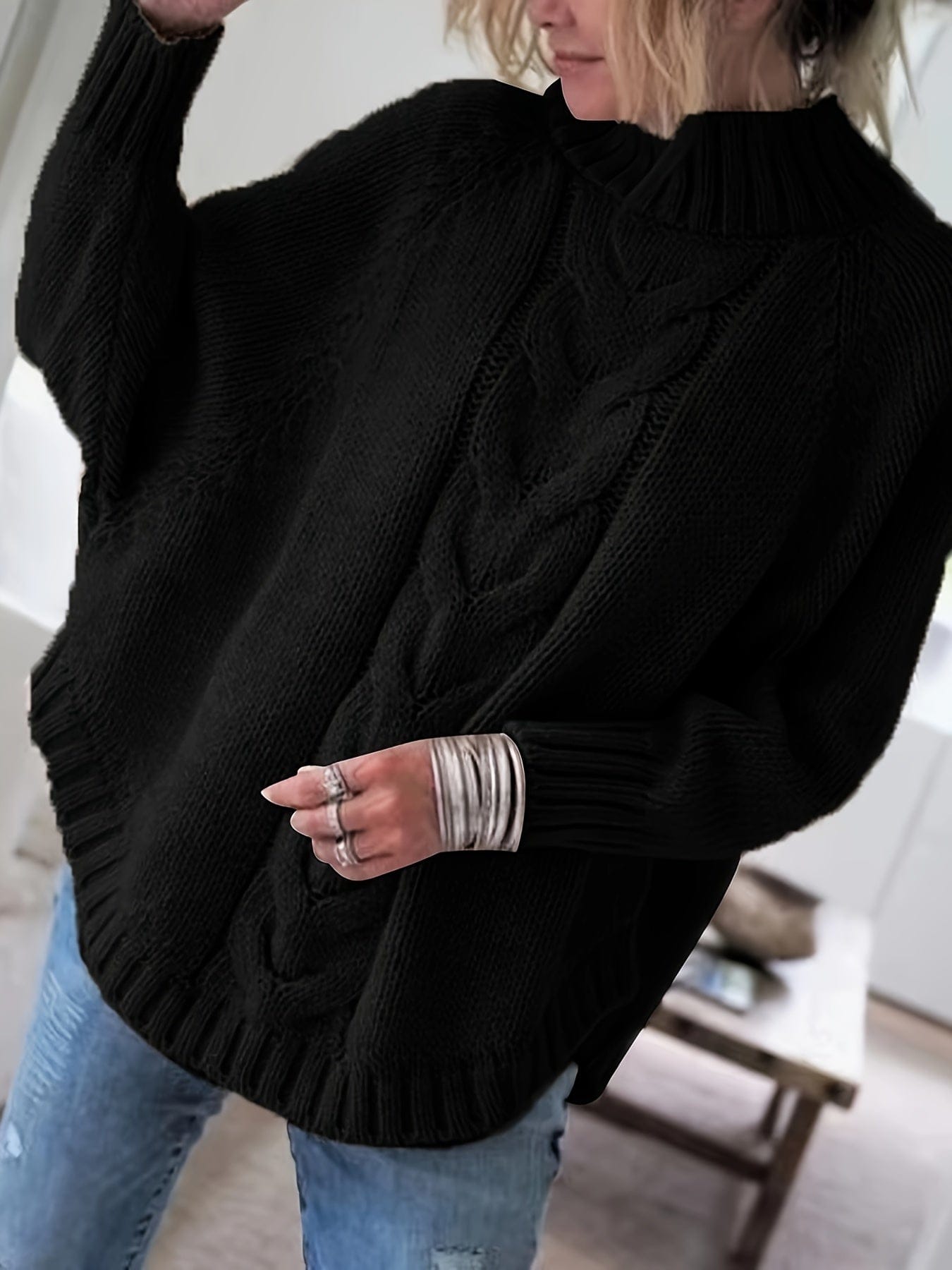 Kvinde iført sweater med høj hals, markante snoninger og afslappet pasform._1