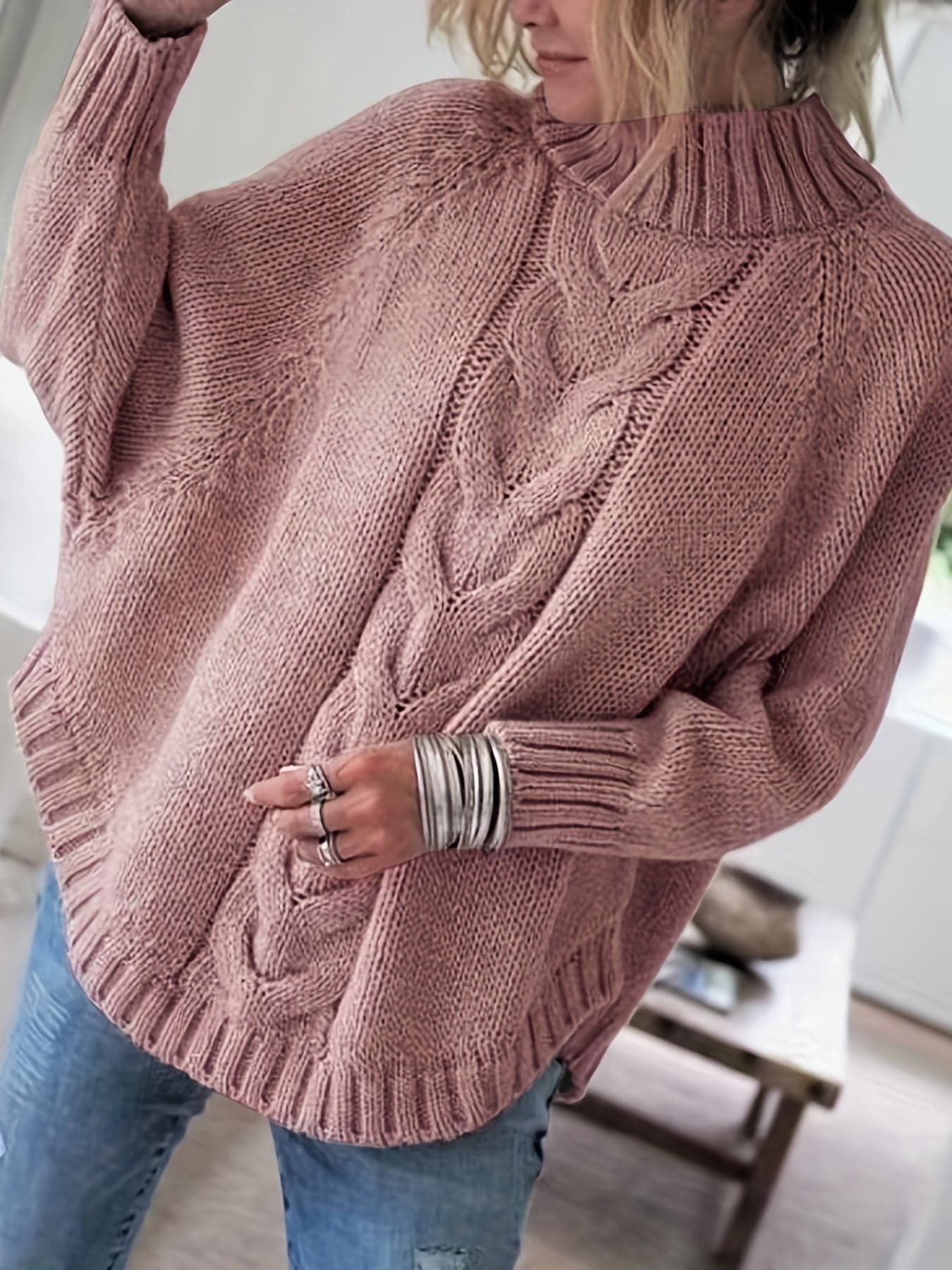 Kvinde iført sweater med høj hals, markante snoninger og afslappet pasform._2