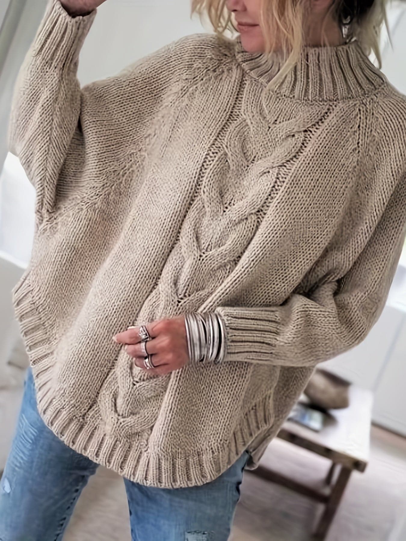 Kvinde iført sweater med høj hals, markante snoninger og afslappet pasform._4