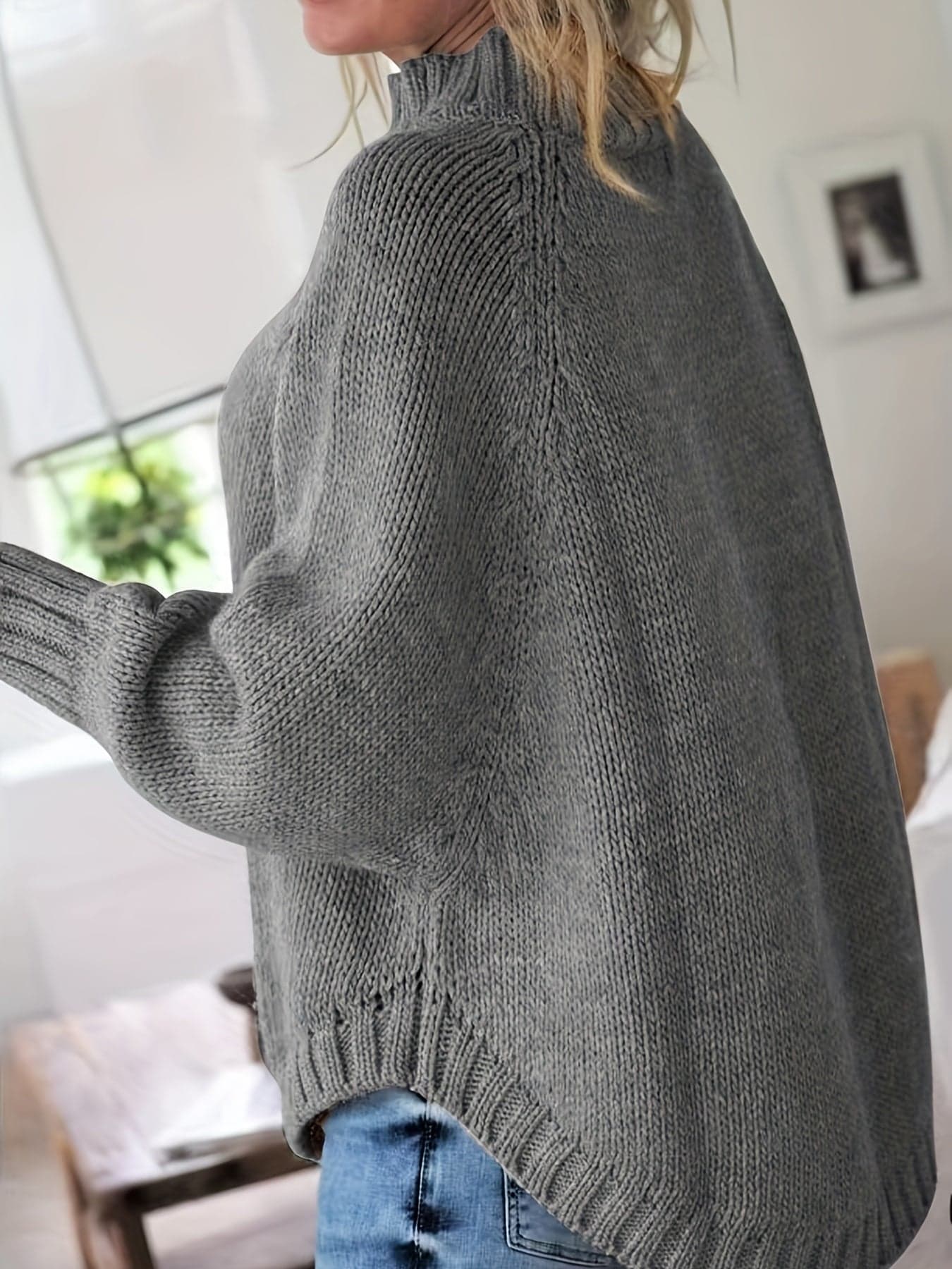 Kvinde iført sweater med høj hals, markante snoninger og afslappet pasform._8