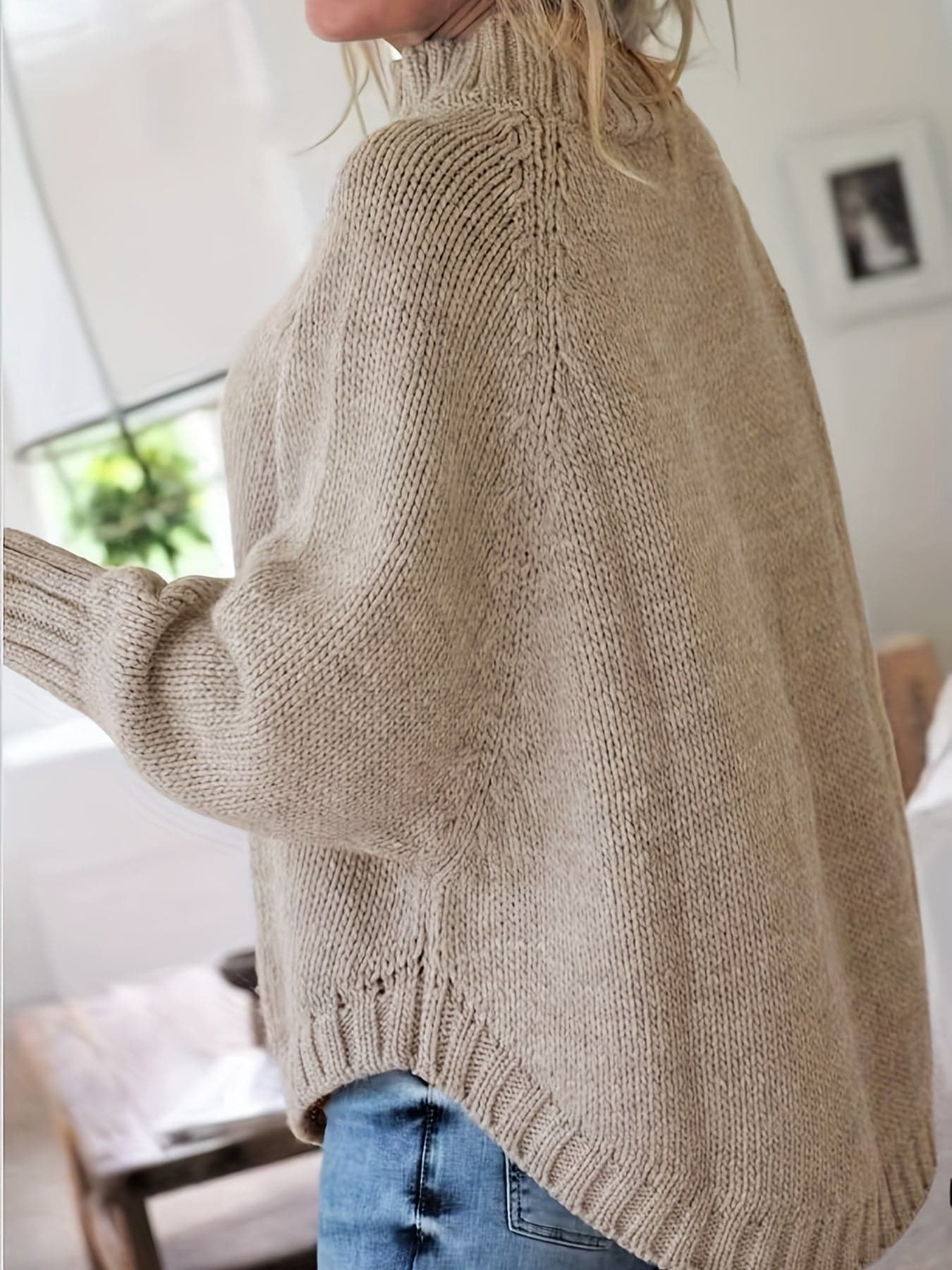 Kvinde iført sweater med høj hals, markante snoninger og afslappet pasform._9
