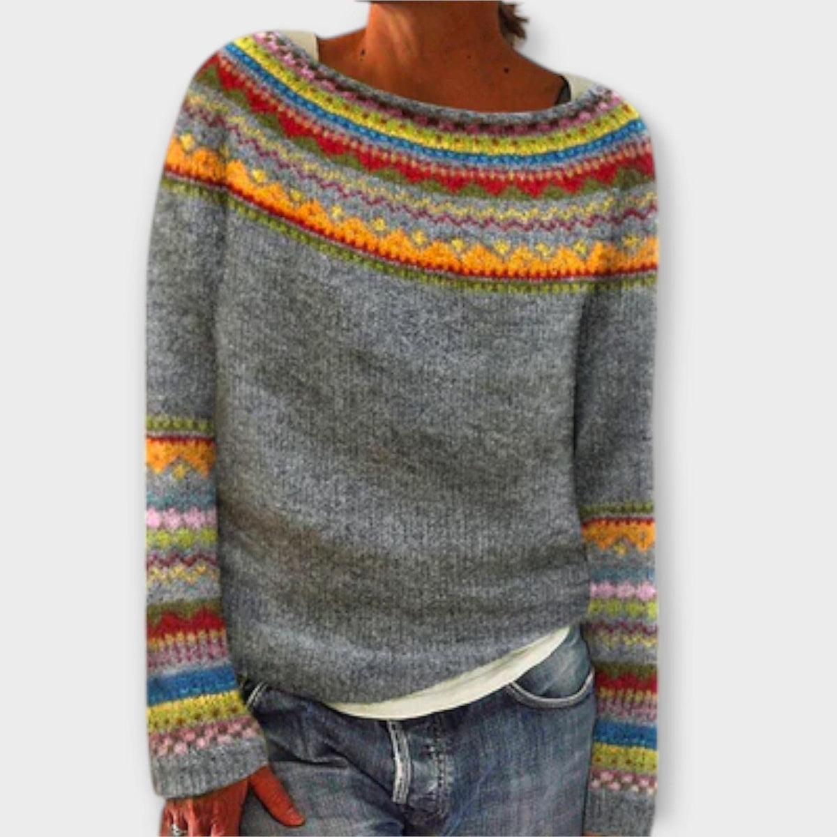 Kvinde iført en grå sweater med farverige strikdetaljer på skuldre og ærmer, kombineret med jeans._0