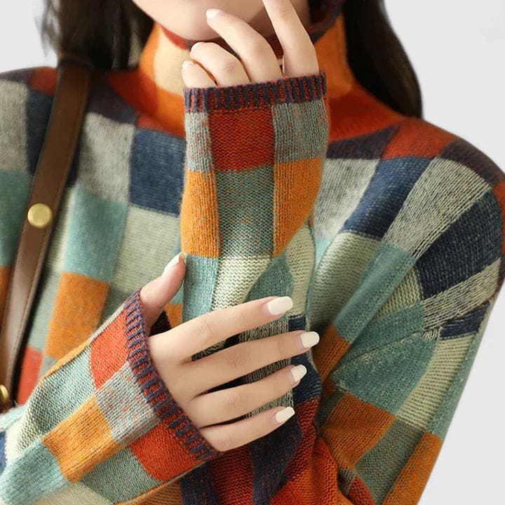 Kvinde iført sweater med farverigt ternmønster i blå, orange, rød og grøn nuancer, stylet med hvide bukser_2