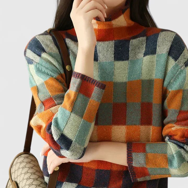 Kvinde iført sweater med farverigt ternmønster i blå, orange, rød og grøn nuancer, stylet med hvide bukser_3