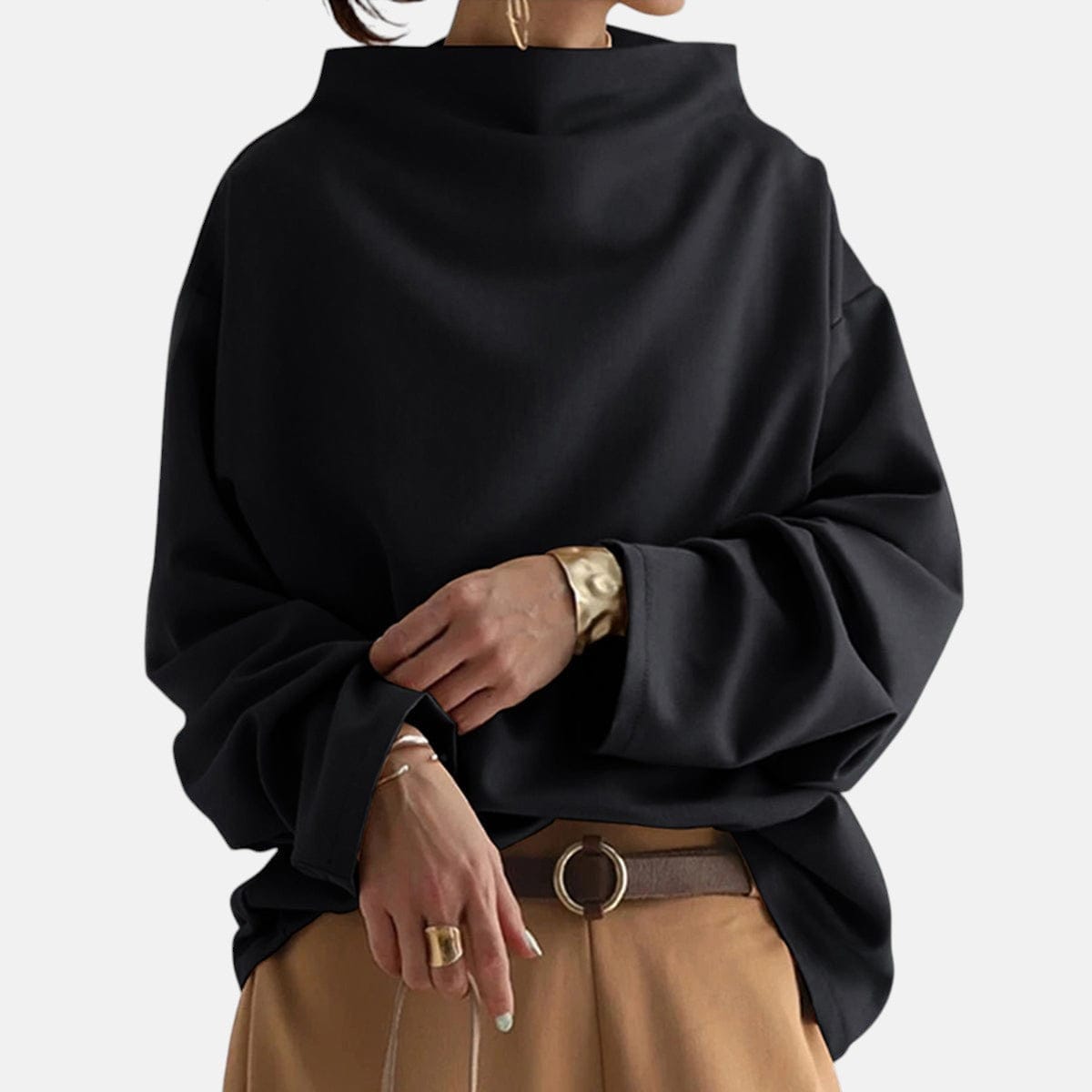 Kvinde iført sort oversized sweater med høj hals, stylet med camelfarvet bukser og bælte._0