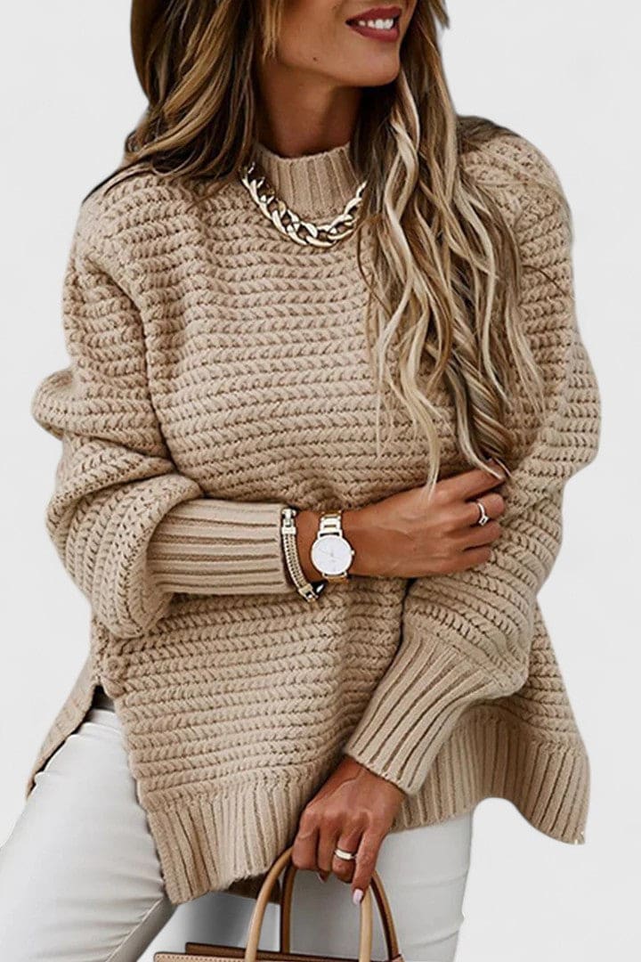 Kvinde iført en sort sweater med struktureret strik, rund hals og løs pasform, stylet med armbåndsur og halskæde._6