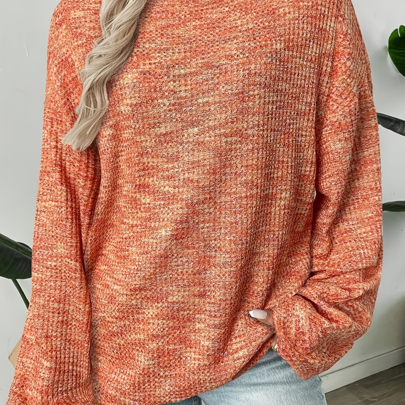 Model iført en rødorange sweater i vaffelstrik med afslappet pasform og lange ærmer, set forfra mod lys baggrund._0
