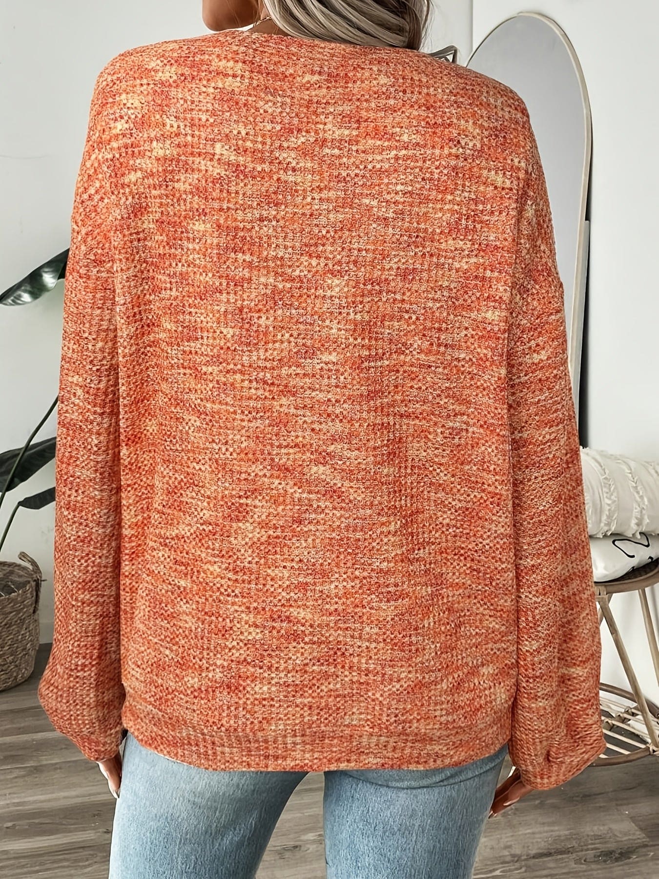 Model iført en rødorange sweater i vaffelstrik med afslappet pasform og lange ærmer, set forfra mod lys baggrund._1