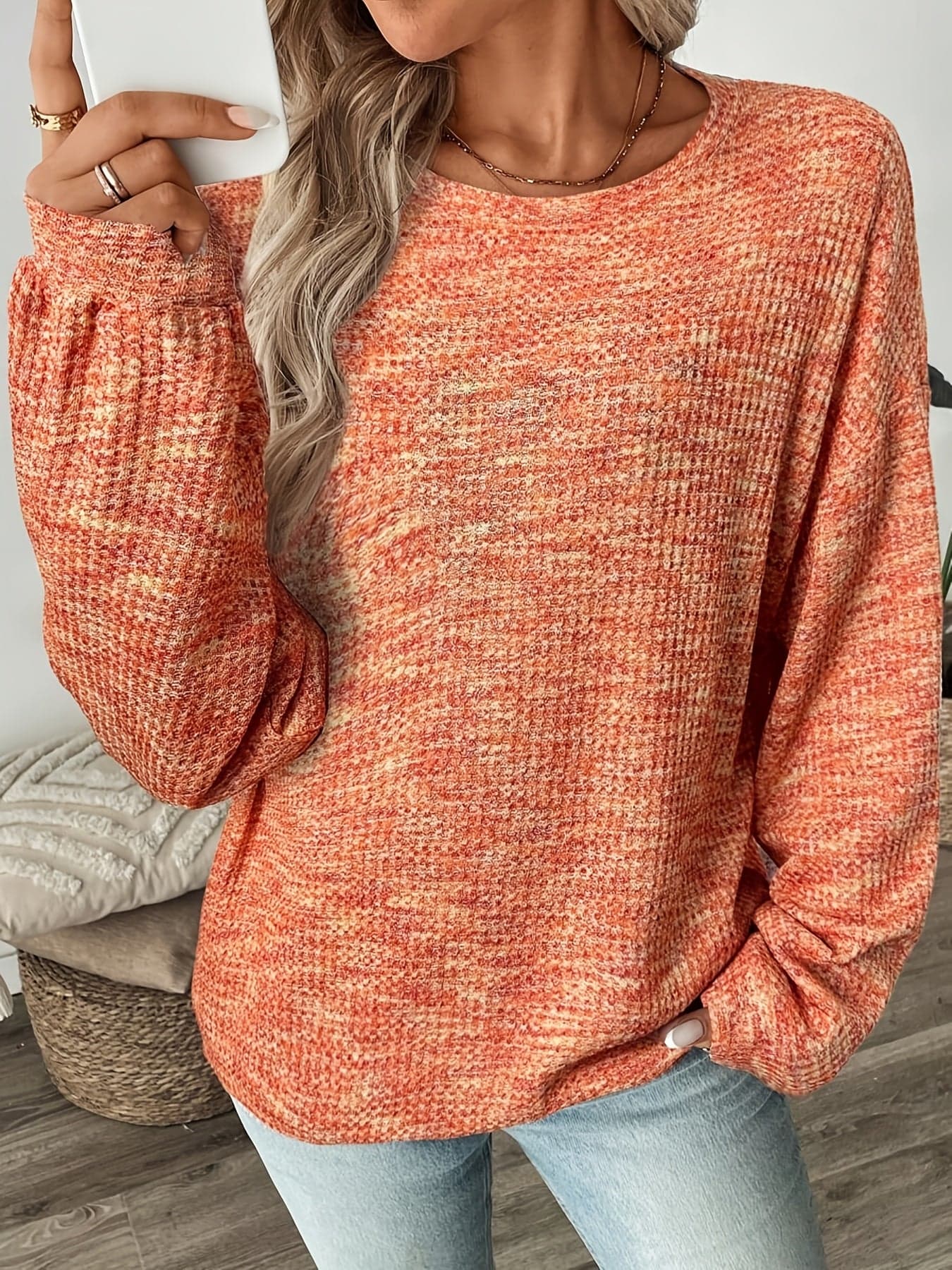 Model iført en rødorange sweater i vaffelstrik med afslappet pasform og lange ærmer, set forfra mod lys baggrund._2