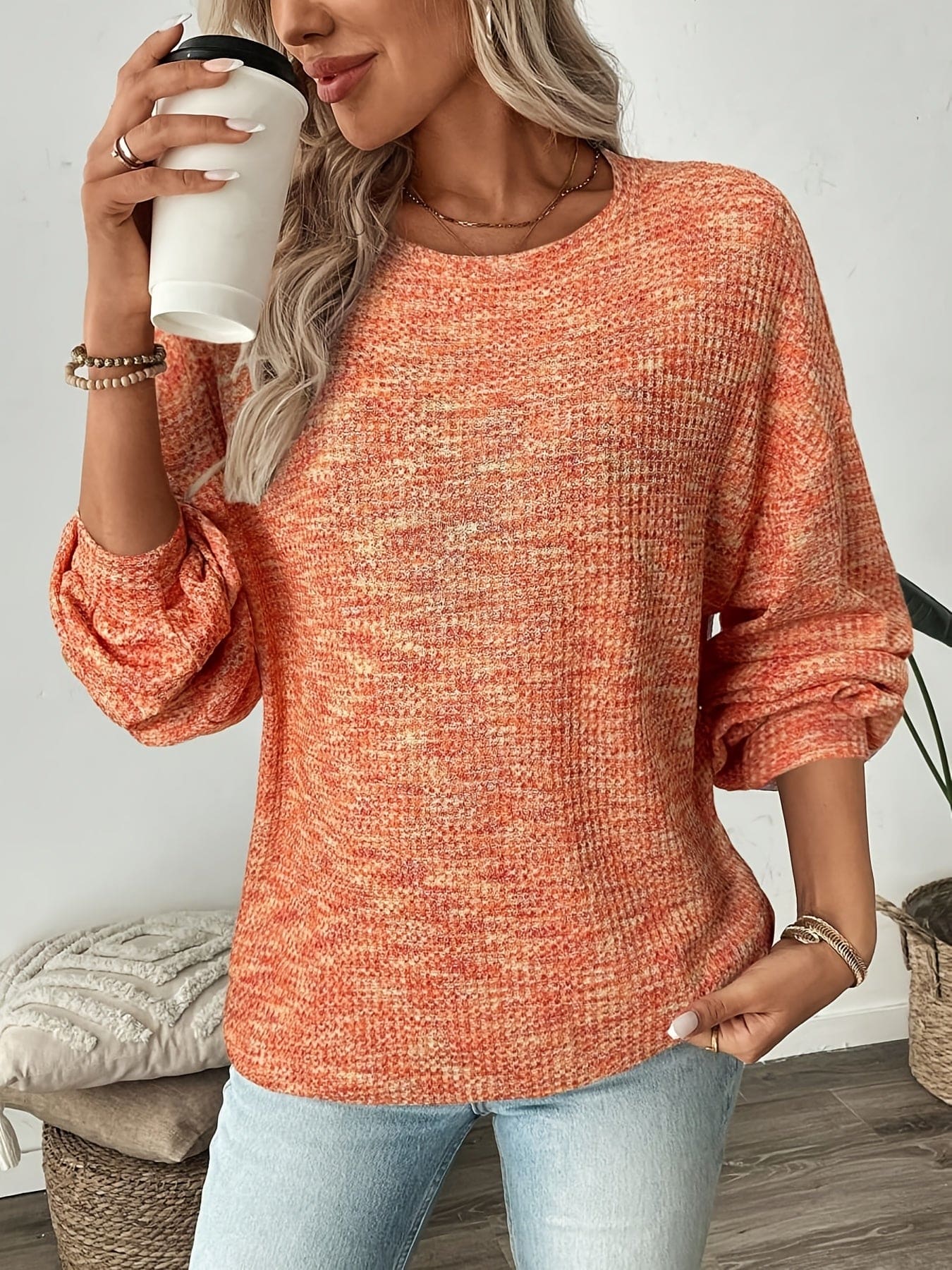 Model iført en rødorange sweater i vaffelstrik med afslappet pasform og lange ærmer, set forfra mod lys baggrund._4