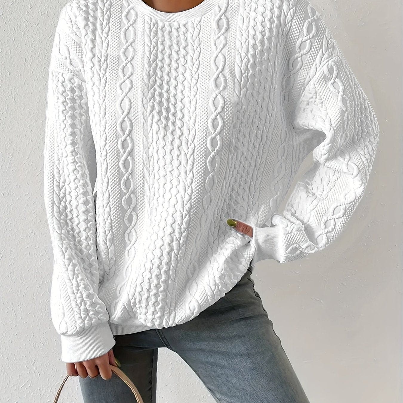 Hvid sweatshirt med struktureret kabelstriksmønster, fotograferet på model mod neutral baggrund._0