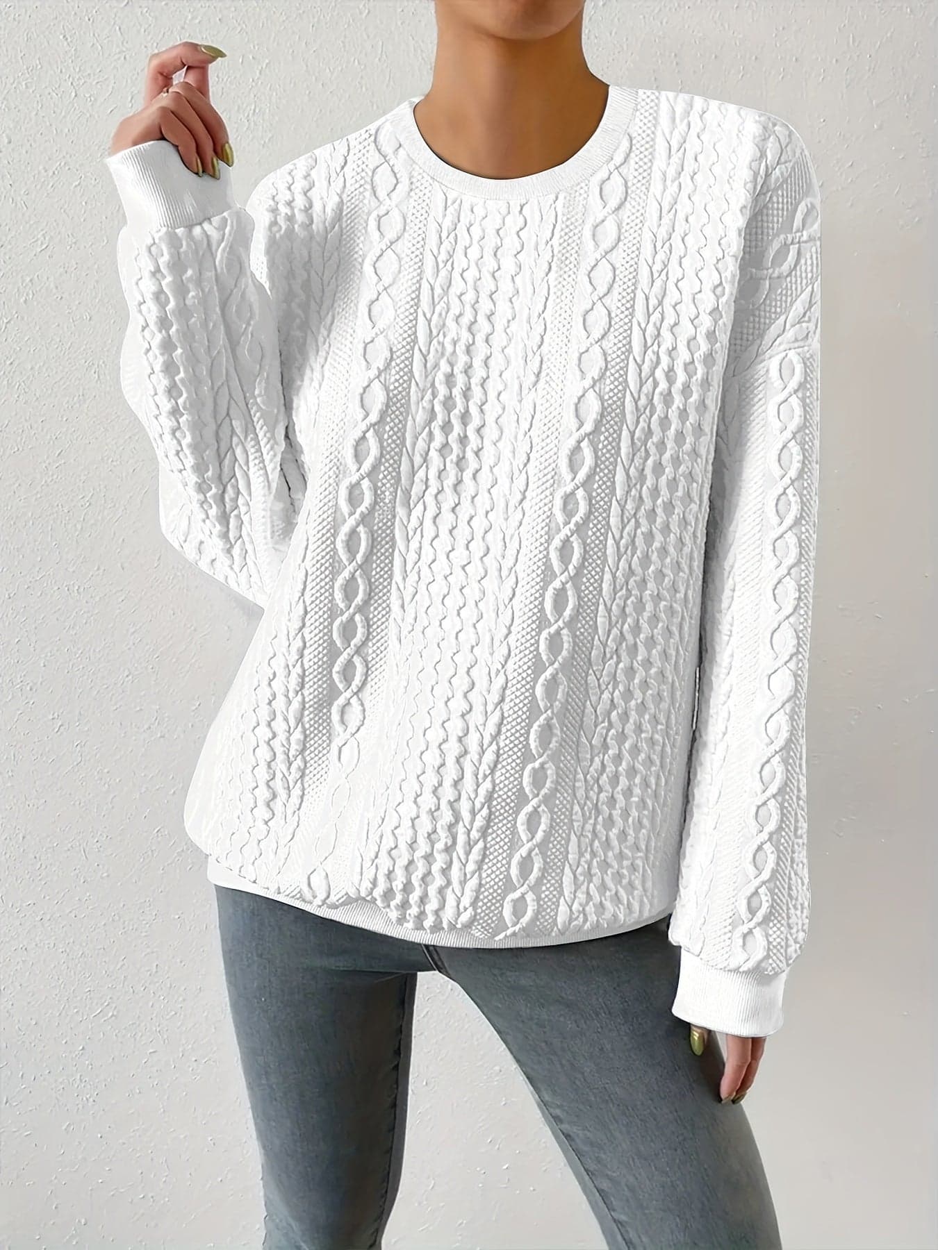 Hvid sweatshirt med struktureret kabelstriksmønster, fotograferet på model mod neutral baggrund._2