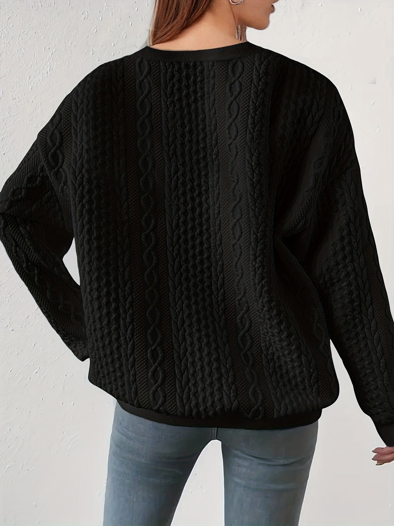 Hvid sweatshirt med struktureret kabelstriksmønster, fotograferet på model mod neutral baggrund._5