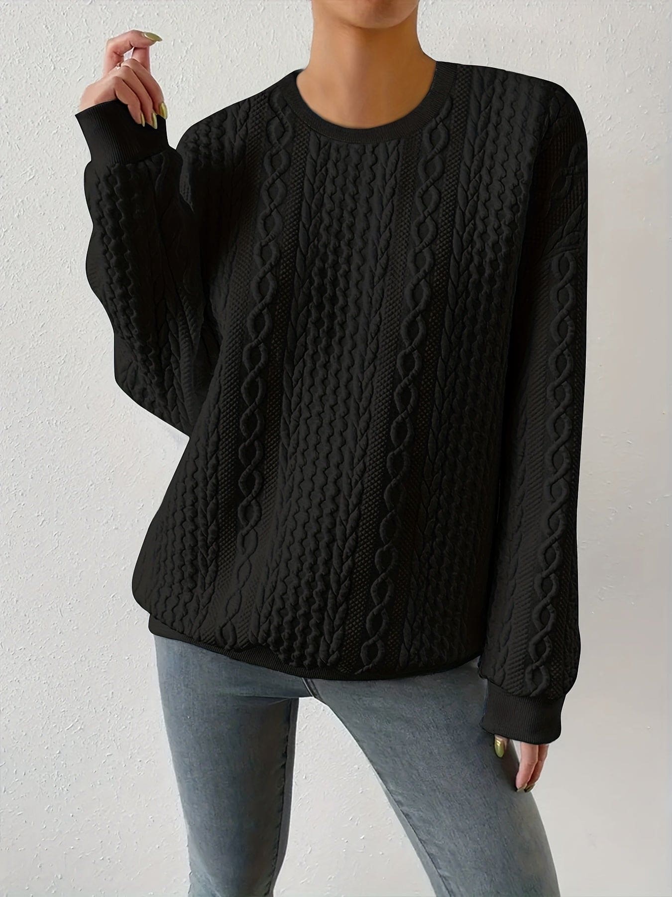 Hvid sweatshirt med struktureret kabelstriksmønster, fotograferet på model mod neutral baggrund._6