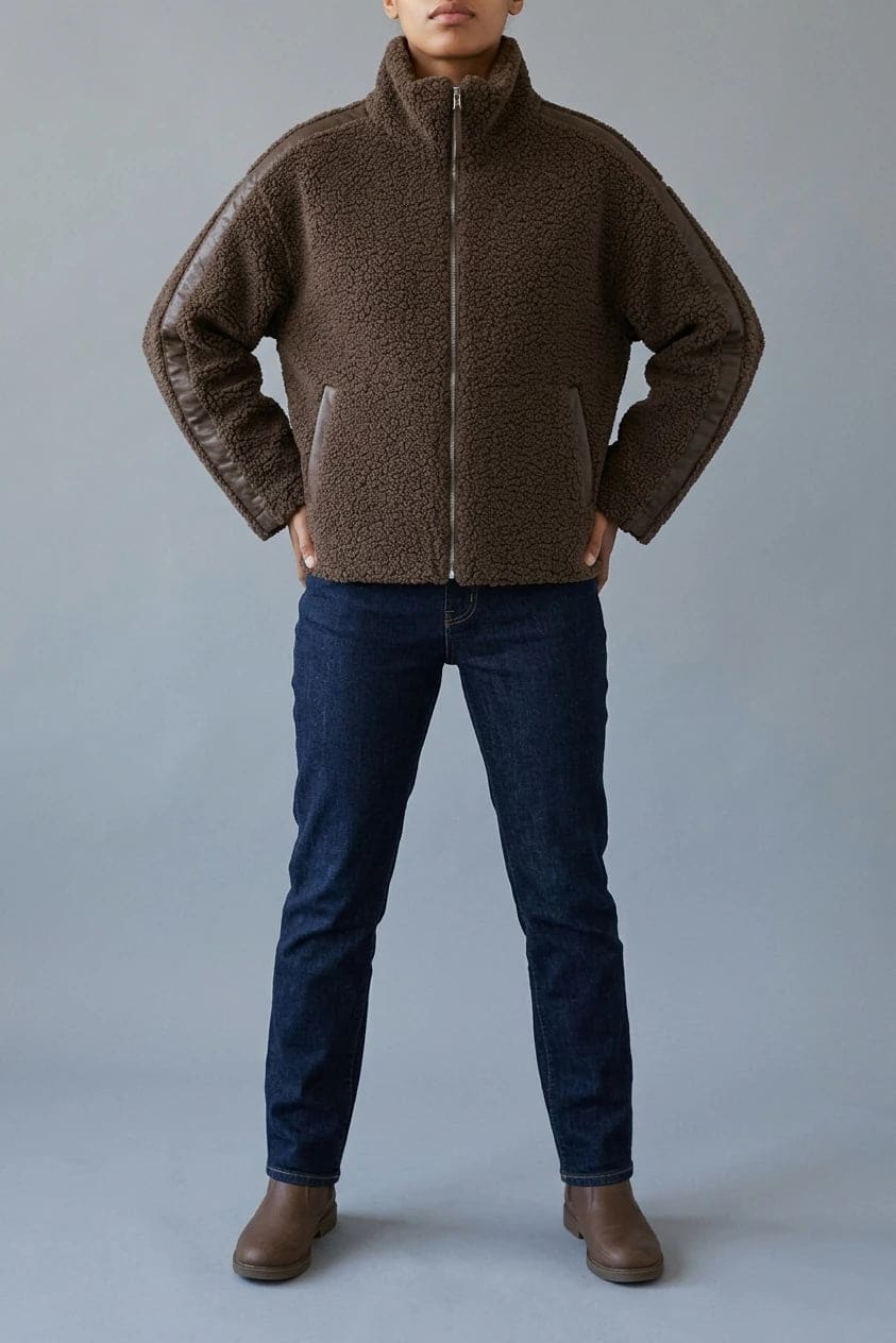 Kort teddyjakke med gennemgående lynlås, høj krave, glatte detaljer på ærmerne og to skrå lommer, styled med jeans og støvler._0