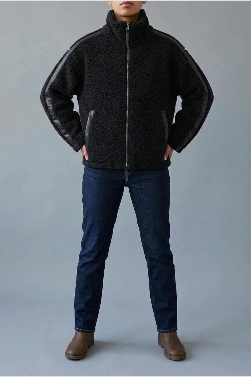 Kort teddyjakke med gennemgående lynlås, høj krave, glatte detaljer på ærmerne og to skrå lommer, styled med jeans og støvler._1