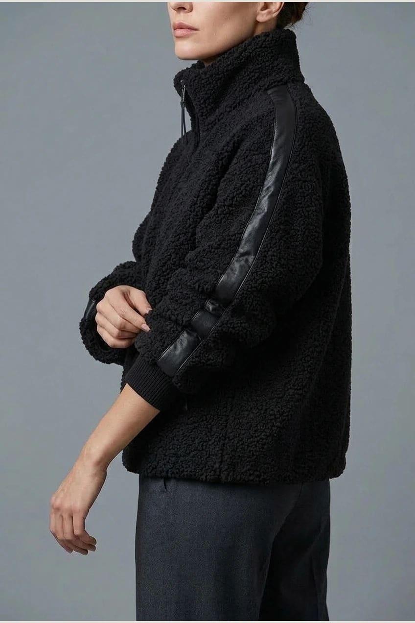 Kort teddyjakke med gennemgående lynlås, høj krave, glatte detaljer på ærmerne og to skrå lommer, styled med jeans og støvler._2