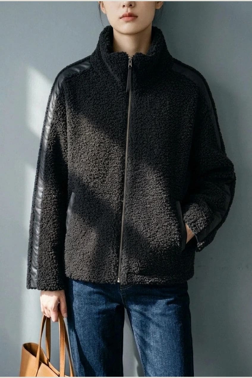 Kort teddyjakke med gennemgående lynlås, høj krave, glatte detaljer på ærmerne og to skrå lommer, styled med jeans og støvler._4