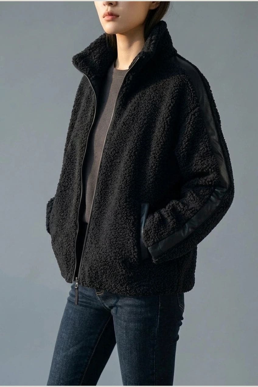Kort teddyjakke med gennemgående lynlås, høj krave, glatte detaljer på ærmerne og to skrå lommer, styled med jeans og støvler._5