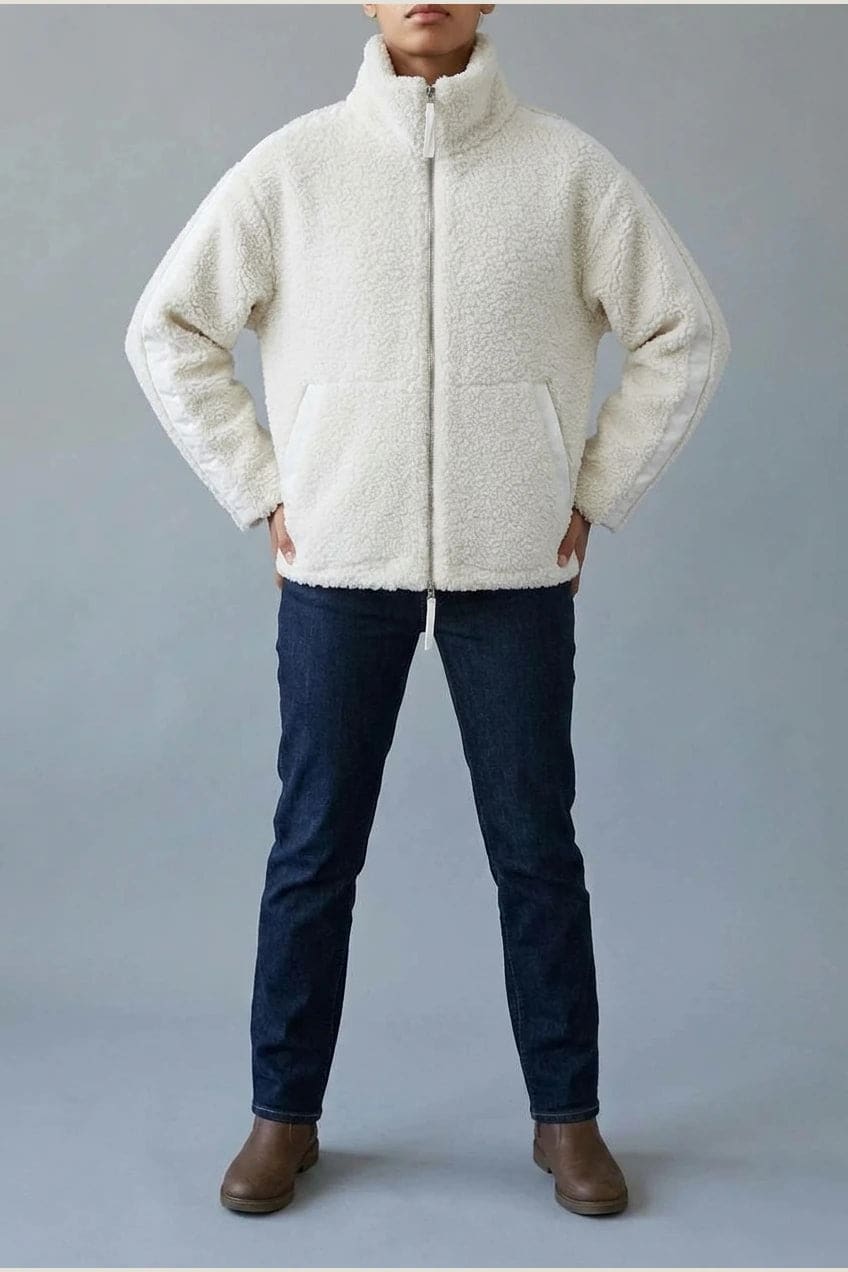 Kort teddyjakke med gennemgående lynlås, høj krave, glatte detaljer på ærmerne og to skrå lommer, styled med jeans og støvler._7
