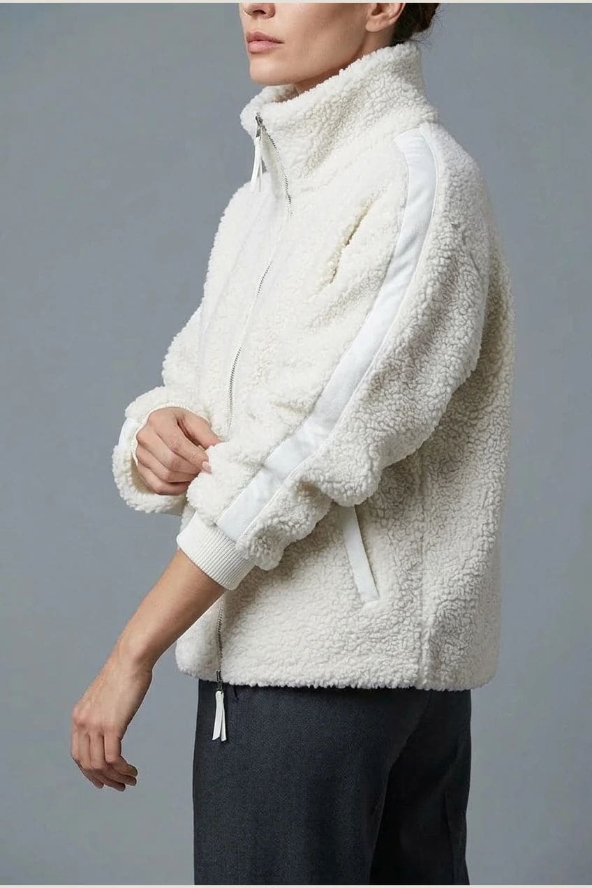 Kort teddyjakke med gennemgående lynlås, høj krave, glatte detaljer på ærmerne og to skrå lommer, styled med jeans og støvler._8
