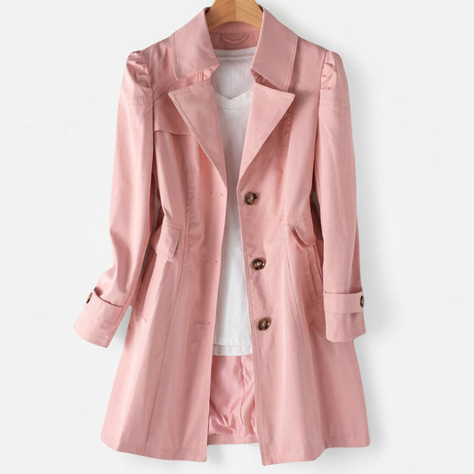 Rosa trenchcoat med klassisk revers, knaplukning og skræddersyet pasform hængende på bøjle over hvid top_0