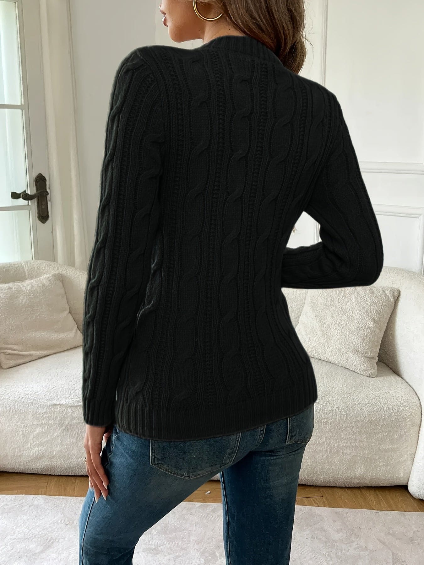 Kvinde iført tætsiddende twiststrikket sweater med rund hals og lange ærmer, stylet med jeans og guldsmykker_2