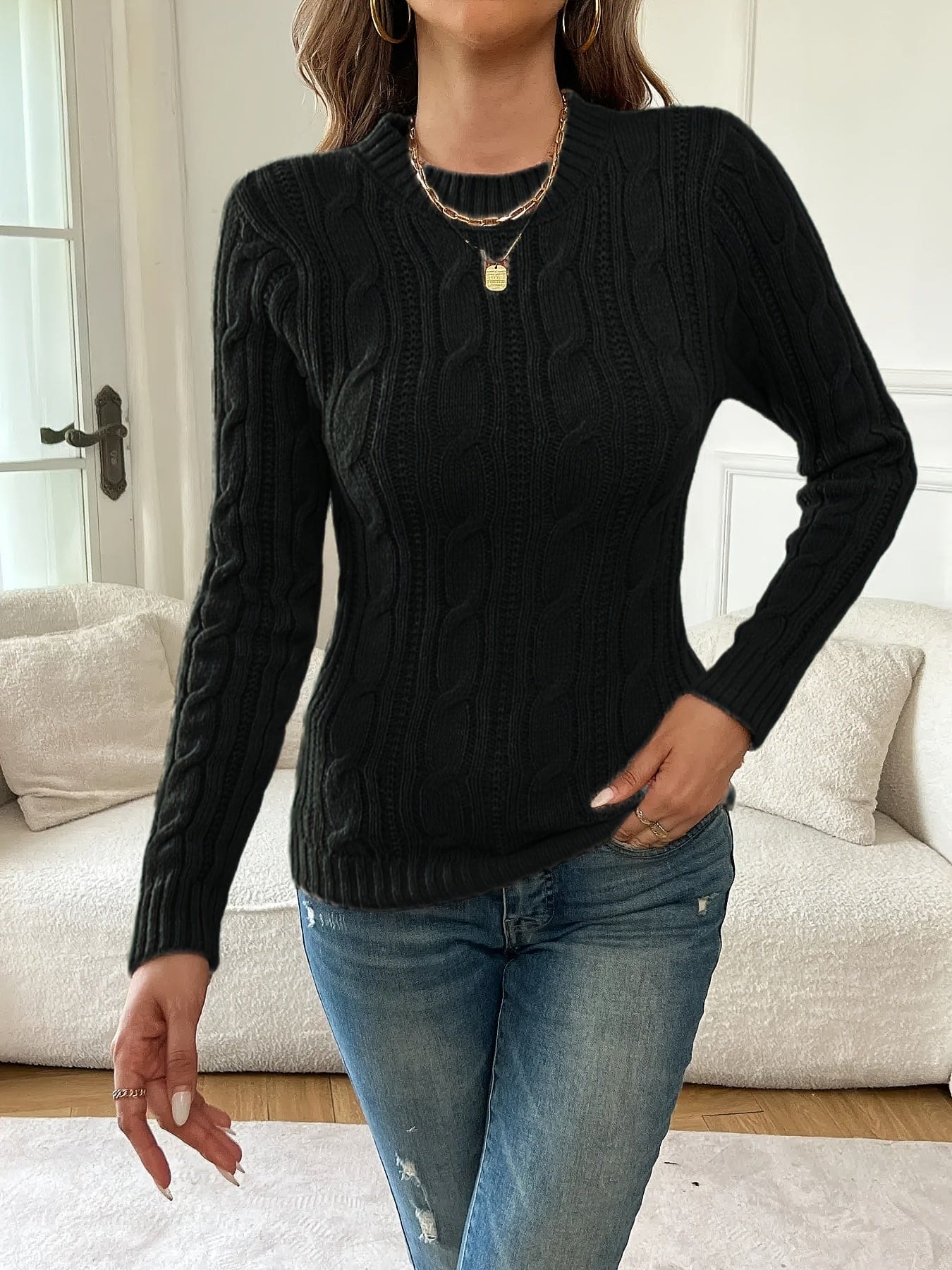 Kvinde iført tætsiddende twiststrikket sweater med rund hals og lange ærmer, stylet med jeans og guldsmykker_3