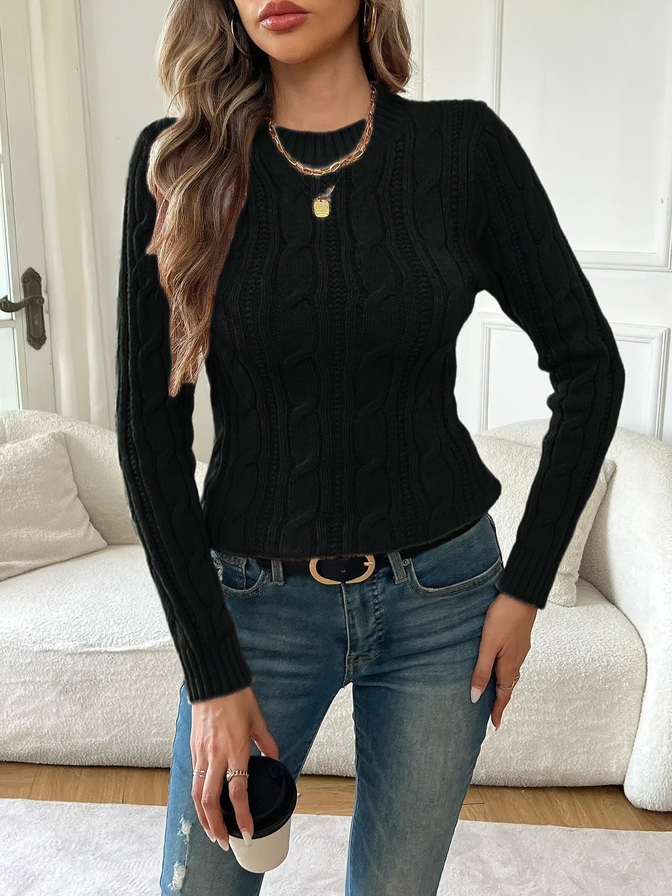 Kvinde iført tætsiddende twiststrikket sweater med rund hals og lange ærmer, stylet med jeans og guldsmykker_4