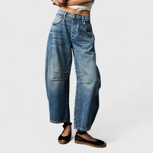 Kvinde iført vide jeans med høj talje og wide-leg pasform samt dekorative detaljer ved knæene, stylet med sorte espadrillos._0