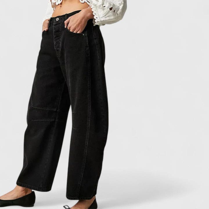 Kvinde iført vide jeans med høj talje og wide-leg pasform samt dekorative detaljer ved knæene, stylet med sorte espadrillos._11