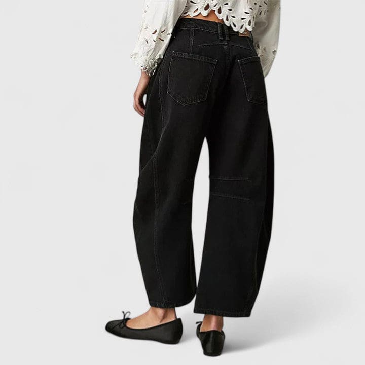 Kvinde iført vide jeans med høj talje og wide-leg pasform samt dekorative detaljer ved knæene, stylet med sorte espadrillos._12