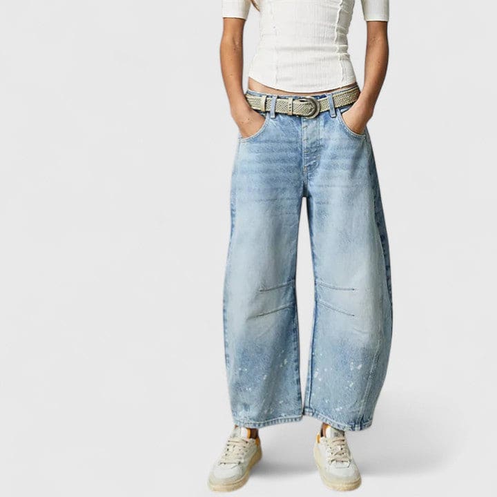 Kvinde iført vide jeans med høj talje og wide-leg pasform samt dekorative detaljer ved knæene, stylet med sorte espadrillos._19