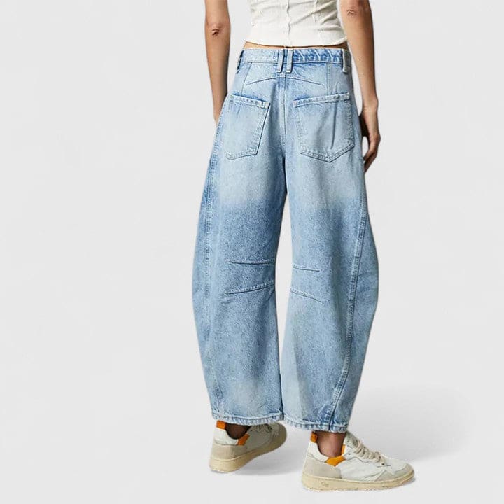 Kvinde iført vide jeans med høj talje og wide-leg pasform samt dekorative detaljer ved knæene, stylet med sorte espadrillos._21