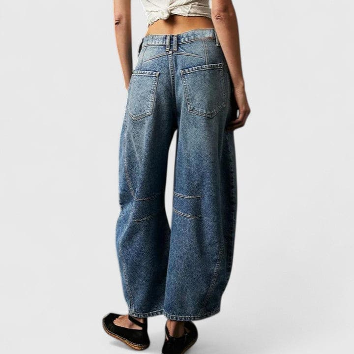 Kvinde iført vide jeans med høj talje og wide-leg pasform samt dekorative detaljer ved knæene, stylet med sorte espadrillos._24