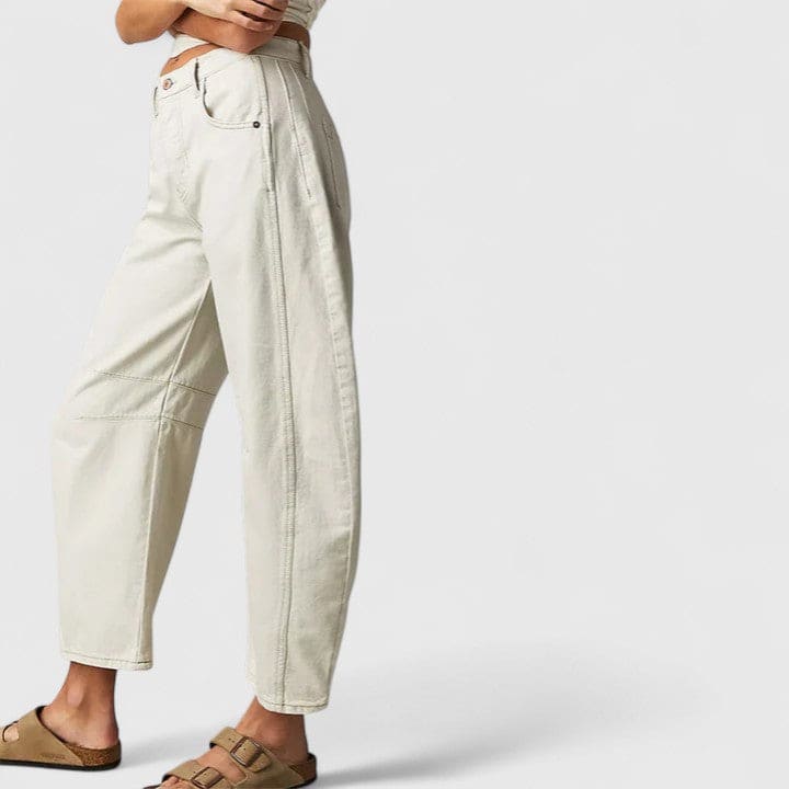 Kvinde iført vide jeans med høj talje og wide-leg pasform samt dekorative detaljer ved knæene, stylet med sorte espadrillos._7