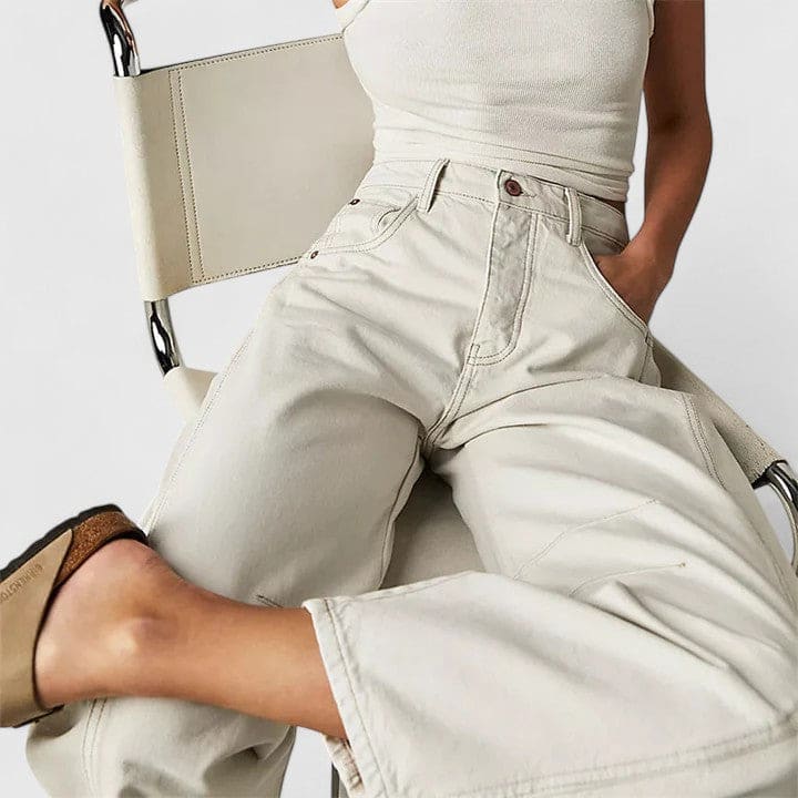 Kvinde iført vide jeans med høj talje og wide-leg pasform samt dekorative detaljer ved knæene, stylet med sorte espadrillos._8