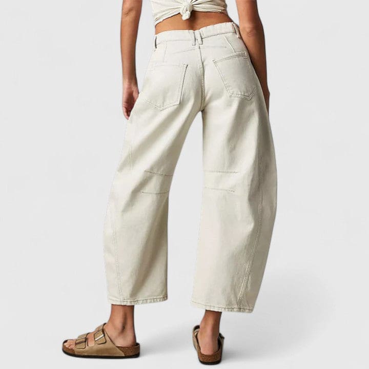 Kvinde iført vide jeans med høj talje og wide-leg pasform samt dekorative detaljer ved knæene, stylet med sorte espadrillos._9