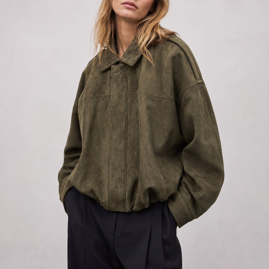 Kvinde iført en oversized vintage bomberjacke i olivengrøn med klassisk krave, afsatte skuldre og elastisk kant ved hoften._0